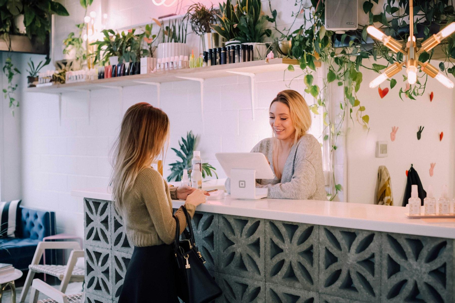 A customer paying at a small shop counter while the clerk smiles